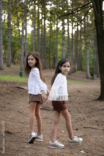 Full length image of a two sisters preschool ages, posing in park