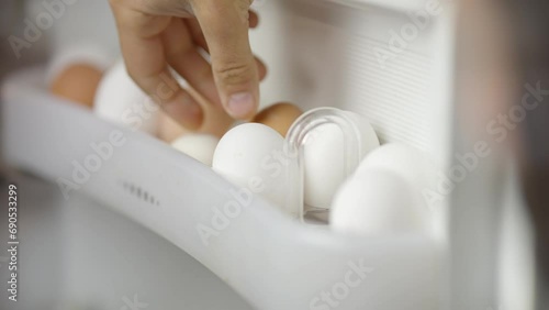 Hand takes white egg from fridge photo