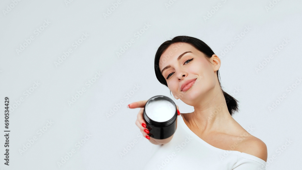 Hands of a young woman holding a container with body and skin care cream. Organic cosmetic product isolated on white background. Advertising and skin care concept. Hands of a young woman holding a container with body and skin care cream. Organic cosmetic product isolated on white background. Advertising and skin care concept.