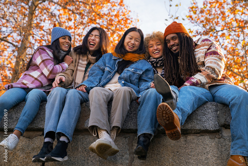 friends laughing happily in park with autumn season colors of different ethnic groups
