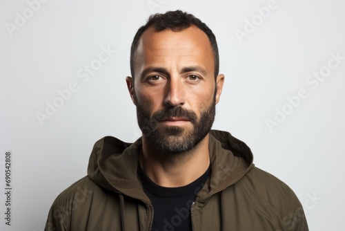 Portrait of a bearded man in a hoodie on a gray background © Nerea