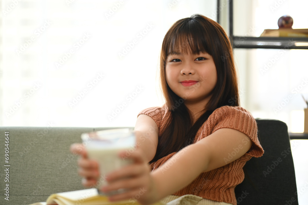 Cheerful Asian girl drinking milk for a breakfast in living room. Cheerful Asian girl drinking milk for a breakfast in living room.