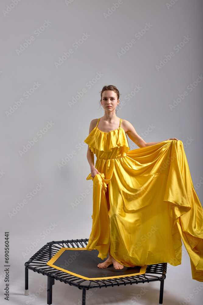girl standing on trampoline, full length shot. beauty, art, creativity, full length isolated grey, white background, ad of dres, model presenting her luxury stylish outfit