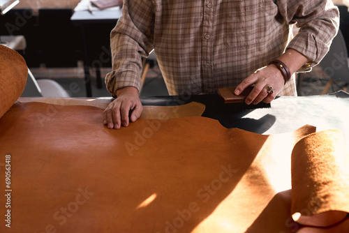 man tries to maintain the integrity of the leather fibers. close up cropped photo, artisan lightly brushes the leather surface.