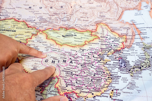 Tourist's hand pointing at world map of China. Located in Asia on world map, China is a country with a large area and a large population. top view