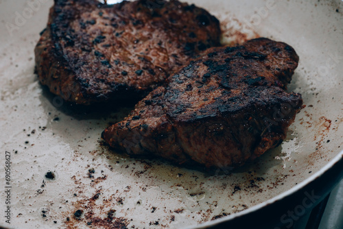 Overcooked beef steak lie white frying pan