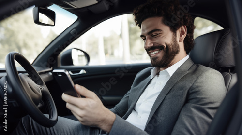 Man smiling joyfully while looking at his phone in his car. © HelenP