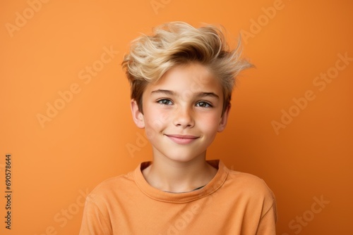 Portrait of cute little boy with blond hair on orange background.