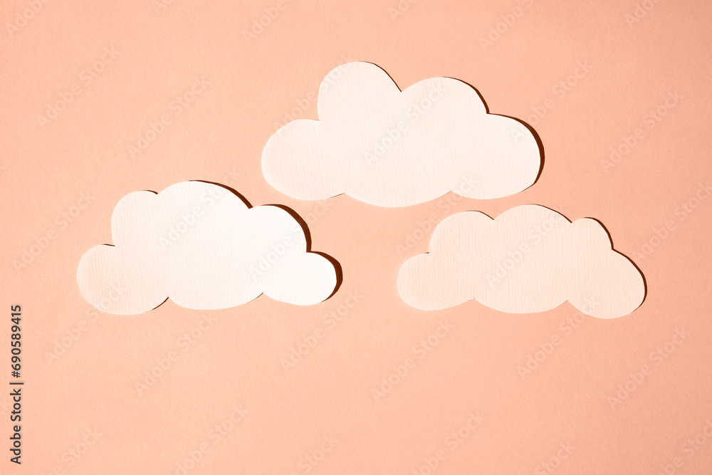 Silhouettes of clouds from white paper. Banner, flat lay, place for text. Peach fuzz is color of year 2024.