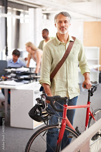 Mature man, business and bicycle in office with portrait and manager of sustainable company. Ceo, boss and job with eco friendly commute in morning with smile in a creative agency of a professional © Yuri A for PeopleImages/peopleimages.com