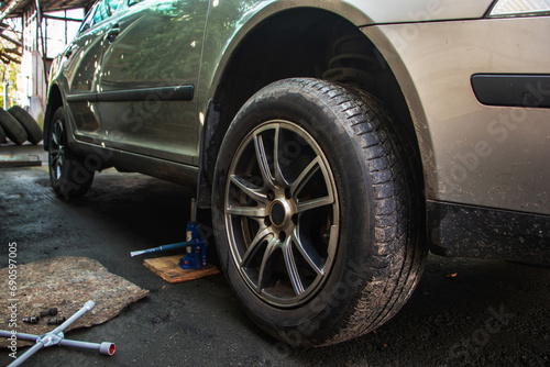 Car lifted by scissor jack without wheel outdoors, closeup. Tire puncture © eliosdnepr