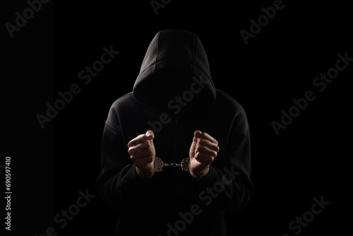 Silhouette of handcuffed male in hoodie, dangerous criminal punished by law. photo