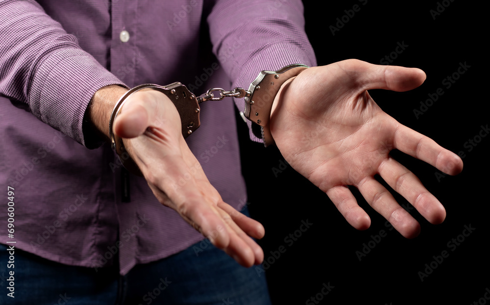Businessman in handcuffs arrested for financial fraud, sitting in interrogation room Businessman in handcuffs arrested for financial fraud, sitting in interrogation room