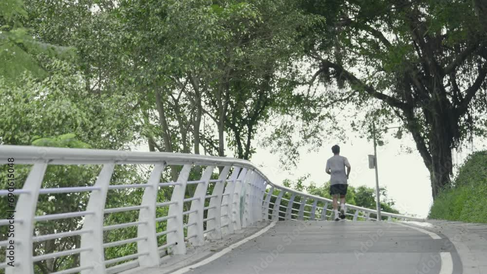 rear view of young asian man jogging running exercising outdoors in park rear view of young asian man jogging running exercising outdoors in park