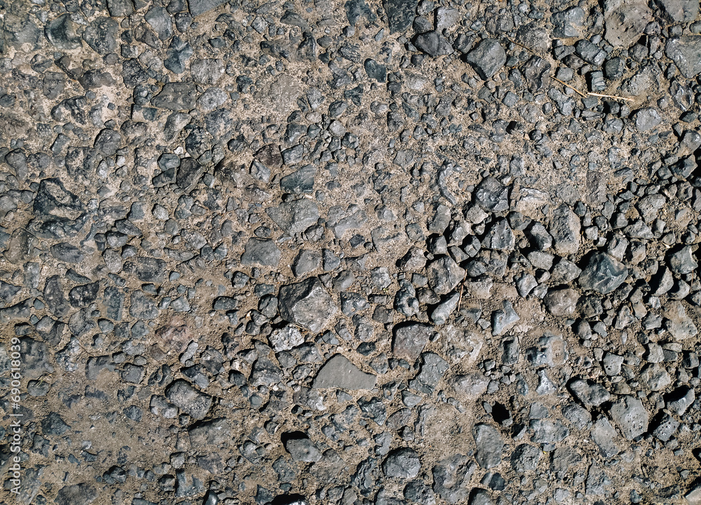 Small cinder stones lie on a dirt road, top view in the rays of the midday sun. Small cinder stones lie on a dirt road, top view in the rays of the midday sun.