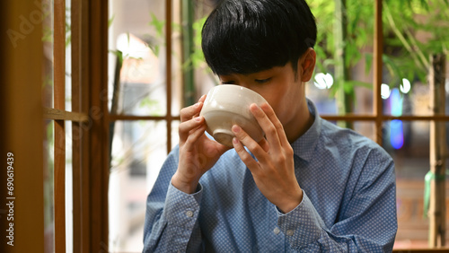 Cropped image of a Young Asian man drinking Japanese traditional matcha tea, The concept of drinking green tea for health photo