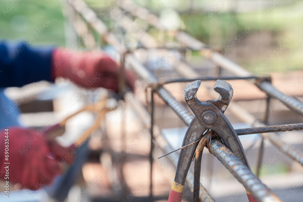 Obraz premium Pincer hanging on steel bar construction material reinforced, Iron rod building structure worker on high workplace site