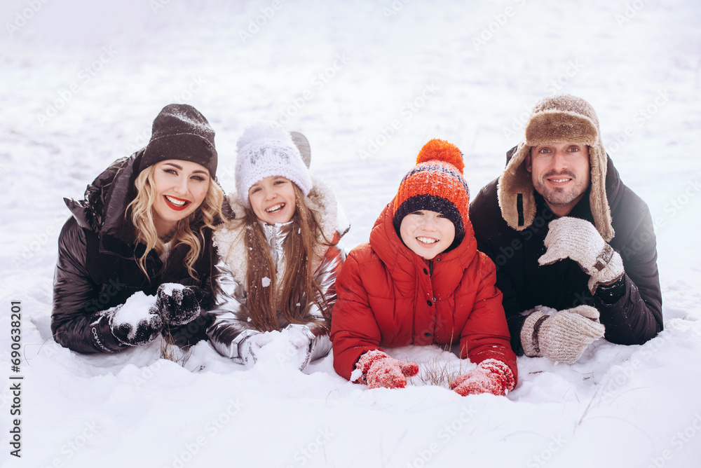 Happy excited cheerful family lying on ground snow having fun winter holiday vacation
