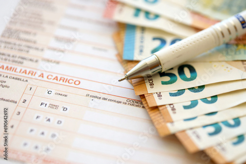 Filling italian tax form process with pen and euro money bills close up. Tax paying period and deadline photo