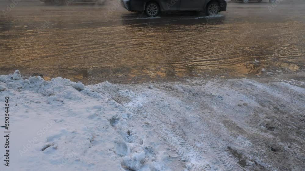 cars drive through boiling water spilled on the road as a result of a