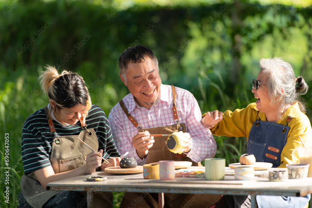 In the pottery workshop, an Asian retired couple is engaged in pottery making and clay painting activities. In the pottery workshop, an Asian retired couple is engaged in pottery making and clay painting activities.