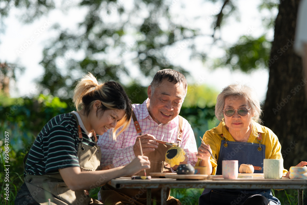 Fototapeta premium In the pottery workshop, an Asian retired couple is engaged in pottery making and clay painting activities.