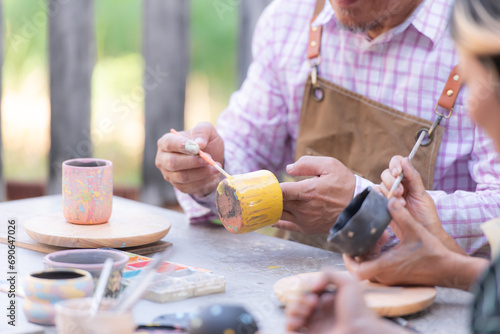 In the pottery workshop, an Asian retired couple is engaged in pottery making and clay painting activities. photo