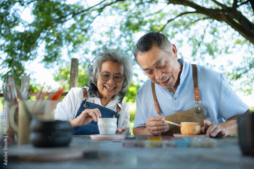 In the pottery workshop, an Asian retired couple is engaged in pottery making and clay painting activities.