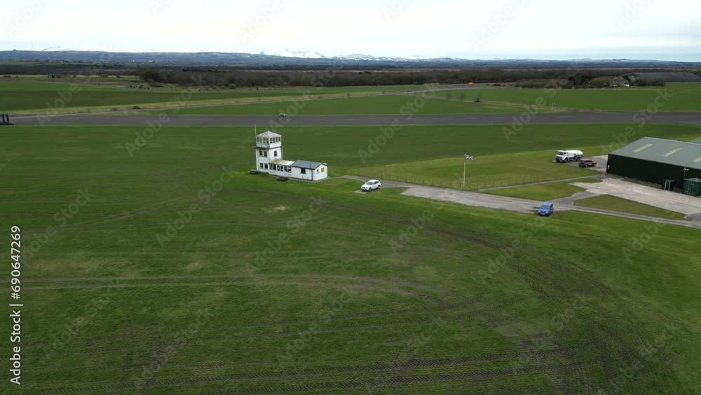 Small Regional Airfield Control Tower with british uk flag on flagpole runway green grass aviation Small Regional Airfield Control Tower with british uk flag on flagpole runway green grass aviation