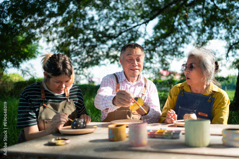 In the pottery workshop, an Asian retired couple is engaged in pottery making and clay painting activities. In the pottery workshop, an Asian retired couple is engaged in pottery making and clay painting activities.