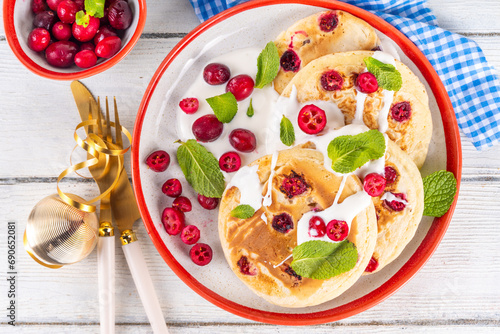 Sweet cranberry pancakes for winter breakfast or brunch. Festive Christmas, New Year breakfast dessert with vanilla creamy topping and fresh cranberries, copy space