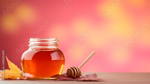 A pink background is used for a jar that has honey and an autumn leaf inside.