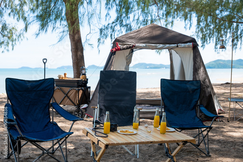 Unwind by the sea  Chairs  picnic table and tent create the perfect camping experience. Sunset  family  and the great outdoors this is where the journey to nature begins. The environment is calling.