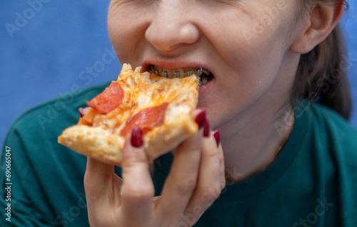 Closeup of woman with dental braces eating slice of pizza