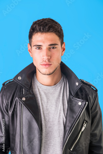 Young handsome man standing in studio shot, wearing black leather jacket and jeans