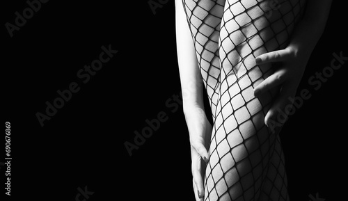 Beautiful female legs in mesh tights in dark lighting. Close-up photo