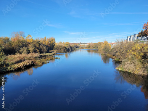 Blue waters of the Tormes River on a cold December morning, both banks can be seen, seen from the most modern bridge in the city