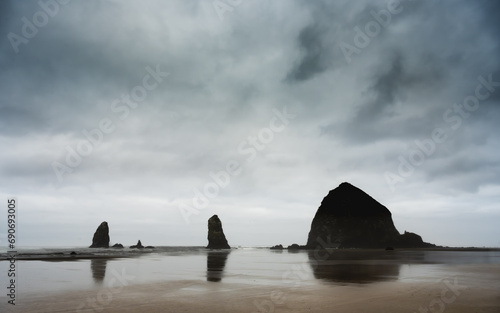Fototapeta Naklejka Na Ścianę i Meble -  Haystack Rock Reflects In The Low Tide Of Canon Beach On Cloudy Morning