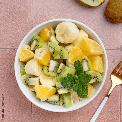 Bowl of healthy fresh fruit salad on ceramic background photo