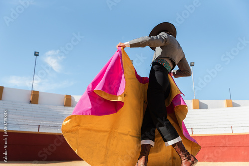 Hispanic matador dancing on sandy arena photo