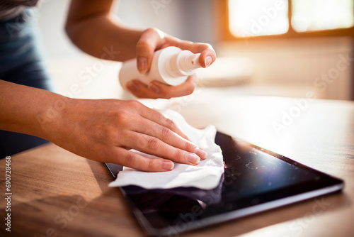 Close up woman hands cleaning tablet screen with cloth and spray photo
