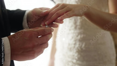 Close up of groom putting wedding ring on bride's finger during ceremony