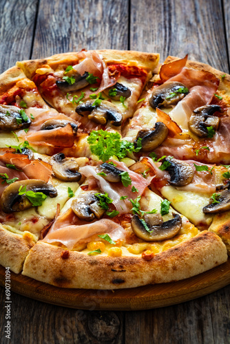 Pizza speck with ham, mozzarella cheese and white mushrooms on wooden table 