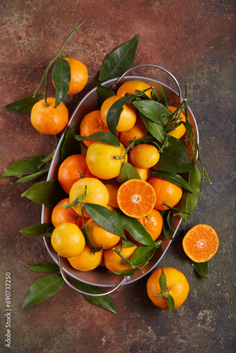 A dish with oranges and tangerines with leaves. Freshly picked up harvest of citrus fruits. 