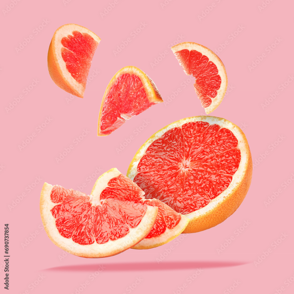 Pieces of grapefruit falling on pink background Pieces of grapefruit falling on pink background