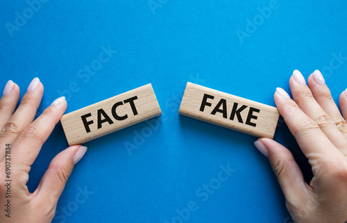 Fact or Fake symbol. Concept word Fact or Fake on wooden blocks. Businessman hand. Beautiful blue background. Business and Fact or Fake concept. Copy space