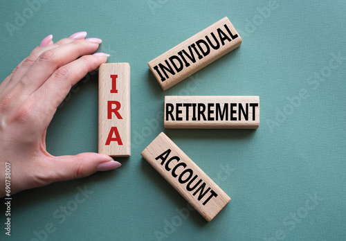 IRA - Individual Retirement Account symbol. Concept word IRA on wooden blocks. Businessman hand. Beautiful grey green background. Business and IRA concept. Copy space. photo