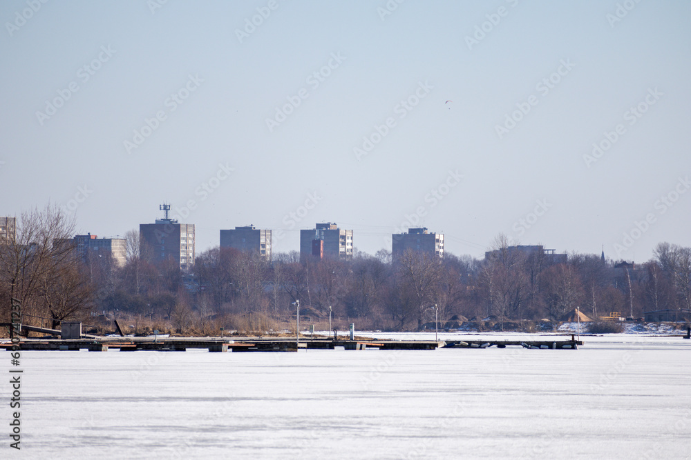 High-rise residential buildings on the bank of a frozen river and a boat dock