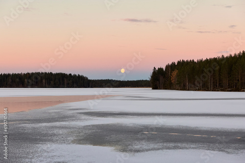 Sunset and moon rise on a lake in winter