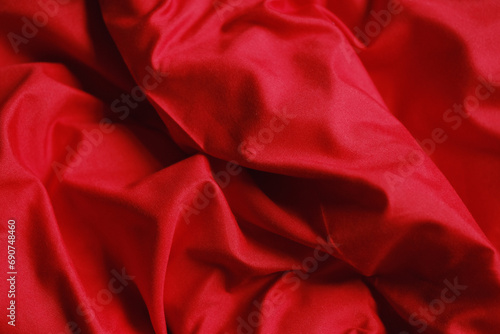 Designer red velvet fabric, rumpled bed after waking up in the morning. Copy space on textiles.